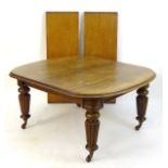 A mid 19thC mahogany dining table with moulded rounded edges and standing on large reeded tapering