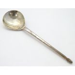 A silver spoon with hammered bowl and acorn finial.