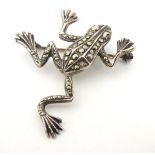 A silver brooch formed as a frog decorated with marcasites and having red stone eyes. 1 ½” long.