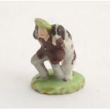 A miniature Rockingham style figure of a man wearing a tam-o-shanter with a dog on an oval base.