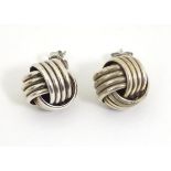 A pair of white metal stud earrings formed as large knots.