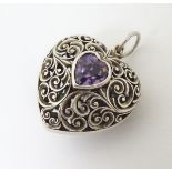 A silver pendant of heart shape with pierced scrolling decoration and central heart shaped amethyst.