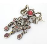 A white metal brooch with bow formed hanger and set with rubies and chalcedony cabochon.