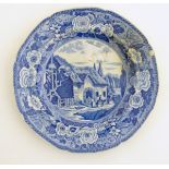 A 19thC blue and white transferware plate depicting a country scene with a thatched cottage,