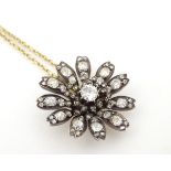 A 9ct gold chain set with a gold and diamond pendant of flower form. The central diamond approx 0.