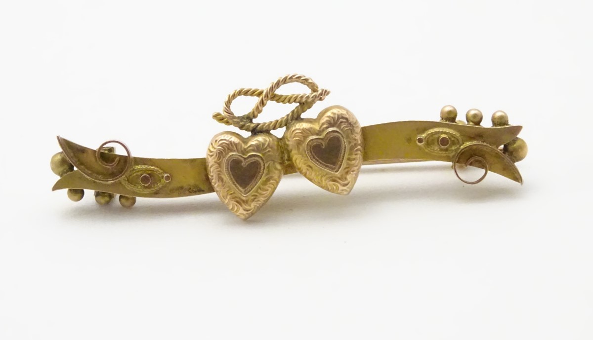 A Victorian 9ct gold bar brooch set with twin hearts, 1 ¾” wide.