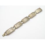 A silver bracelet set with various panels with floral, butterfly, acorn and oak leaf decoration etc.
