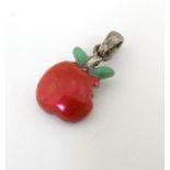 A silver pendant / charm formed as a bitten apple with enamel decoration.
