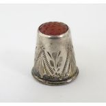 A small silver thimble set with carnelian hardstone tip.