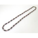 A silver and white metal necklace set with pink cats eye beads.