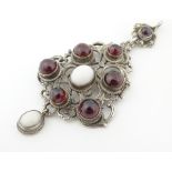 A Continental silver and white metal pendant set with opal and garnet cabochon.