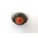 A silver ring set with central coral cabochon bordered by marcasites in an Art Deco setting.