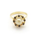 An 18ct gold ring set with central pearl bordered by garnets.