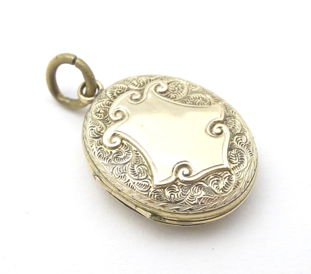 A Victorian yellow metal locket with engraved decoration and cartouche 1 /4" long