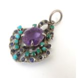 A white metal pendant set with central amethyst and with turquoise and blue spinel. 1 ¾” long.