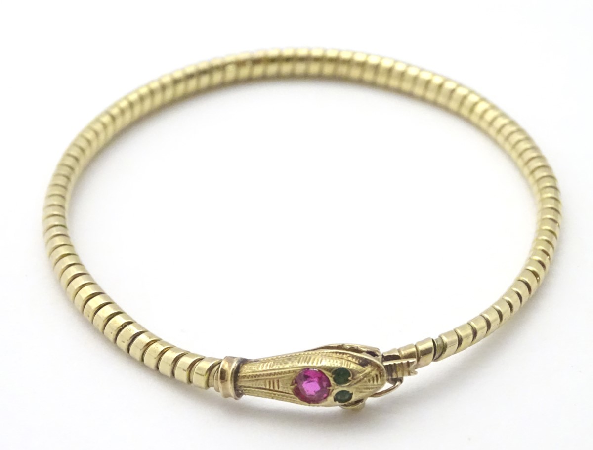 An 18ct gold bracelet formed as a snake / serpent set with ruby spinel to head and green paste eyes.