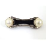 A white metal brooch set with onyx and pearls in an Art Deco setting.