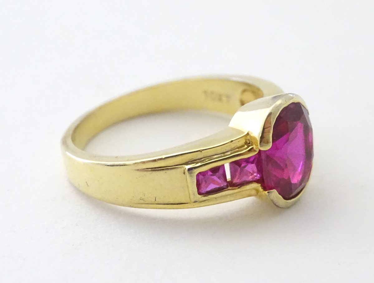 A 10ct gold ring set with central ruby flanked by 2 further rubies to each shoulder. - Image 3 of 5