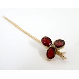 A 9ct gold stick pin set with trio of garnets and central seed pearl. 2” long.