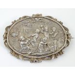 A white metal brooch of oval form decorated to centre with putti in a classical setting depicting