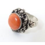 A Continental white metal ring set with coral cabochon.