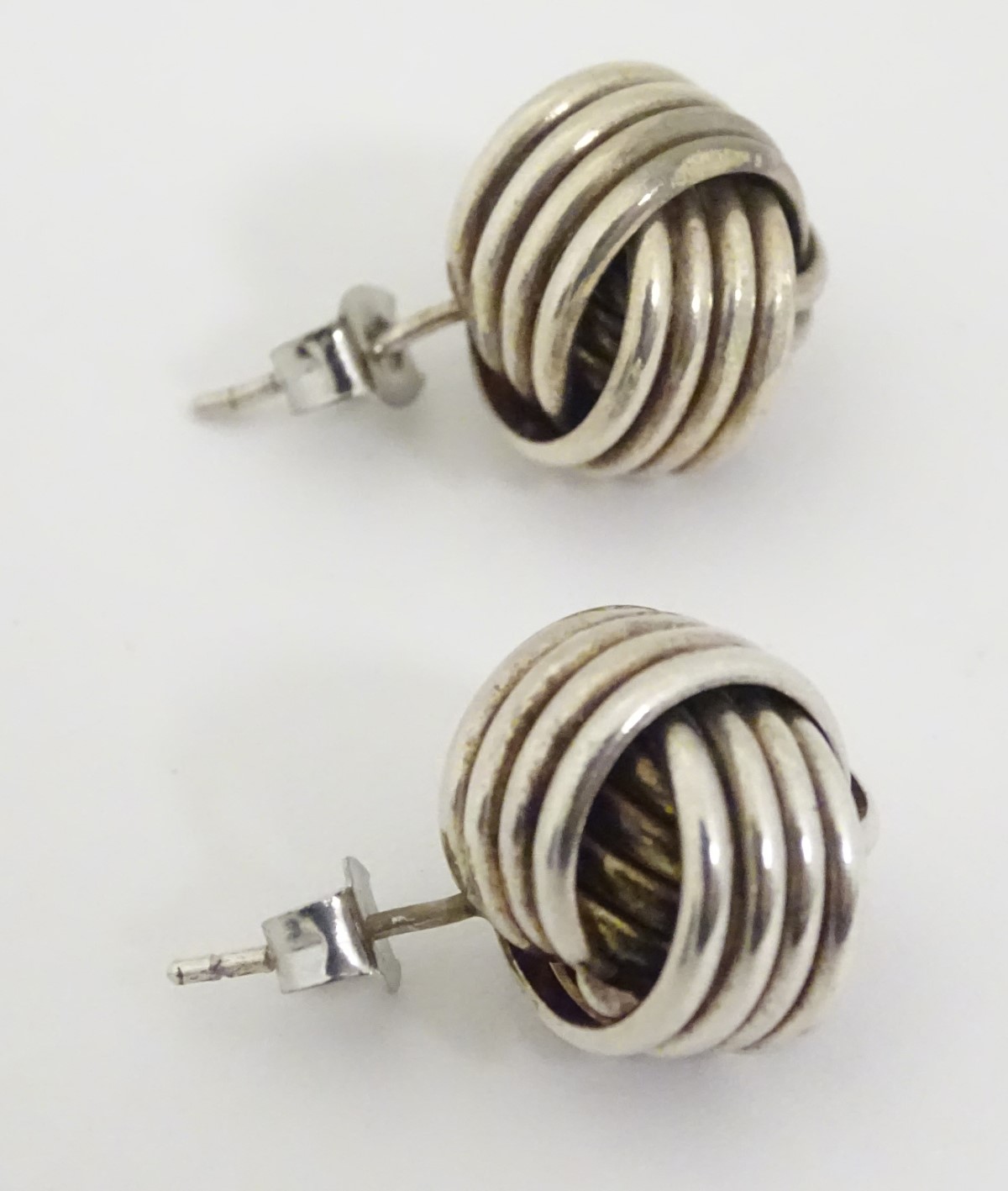 A pair of white metal stud earrings formed as large knots. - Image 2 of 4