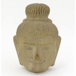 A model of a sandstone Buddha head with elongated earlobes and stylised plaited hair. Approx.