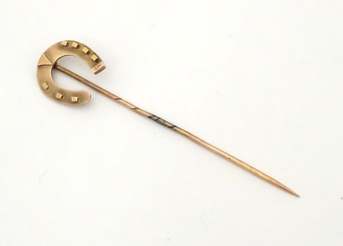 A Victorian 9ct gold stick pin surmounted by a horseshoe.