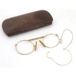 A cased pair of Edwardian pince nez spectacles / glasses with a yellow metal frame,