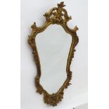 A mid / late 20thC gilt wood mirror with a carved floral frame. 19" wide x 32" high.
