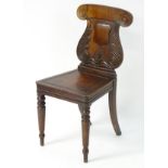 A mid 19thC mahogany hall chair with a lyre shaped back, scrolled ears and foliate carving,