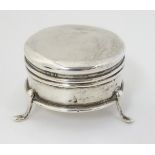 A small silver ring box of circular form on three outswept feet.