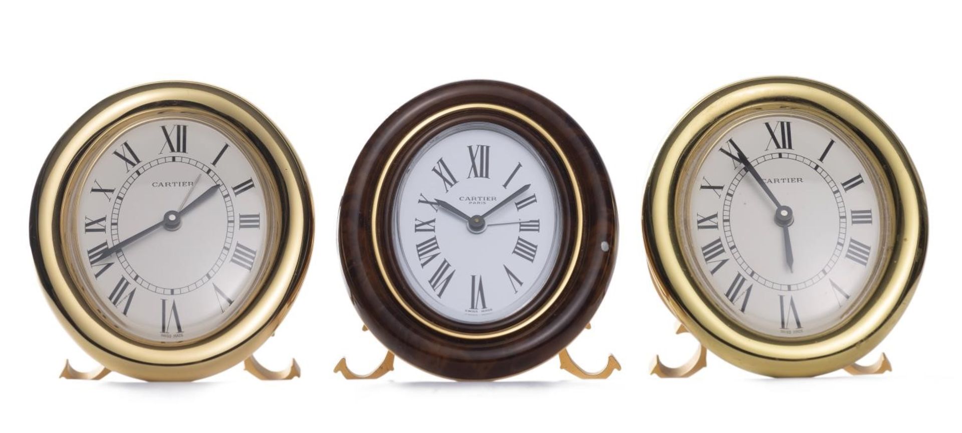 Cartier, Must de, 3 pendulettes réveil à boîtier de forme ovale en métal doré [...]