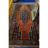 A RED GROUND PERSIAN RUG, with central blue medallion and borders (worn and holed), 106cm x 240cm