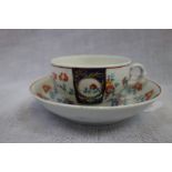 A FIRST PERIOD WORCESTER CUP AND SAUCER with Royal blue and gilt decoration and panels with exotic