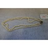 A DOUBLE STRAND CULTURED PEARL NECKLACE, each pearl knotted, with a yellow gold clasp set with a