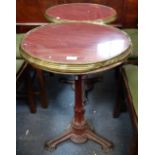 A PAIR OF FRENCH BRASS EDGED CAFE TABLES, with cast iron bases and composite tops, each 52cm