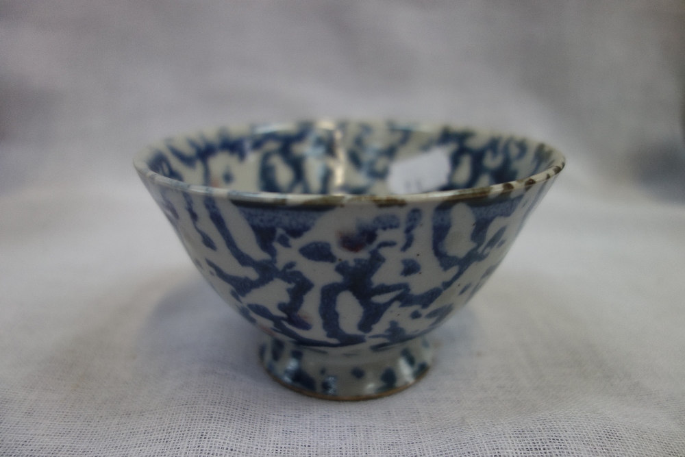 AN ORIENTAL BOWL, with irregular dabbed blue underglaze blue, and some red glaze spots