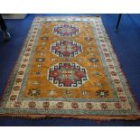A GOLD GROUND RUG with three medallions worked with geometric designs and blue and cream borders,
