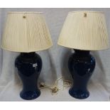 A PAIR OF LARGE BLUE CERAMIC TABLE LAMPS, of vase form with cream pleated silk shades, 71cm high