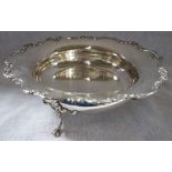 A SHALLOW CIRCULAR SILVER DISH with embossed scalloped edge, on raised feet, 25cm diam, approx 21.