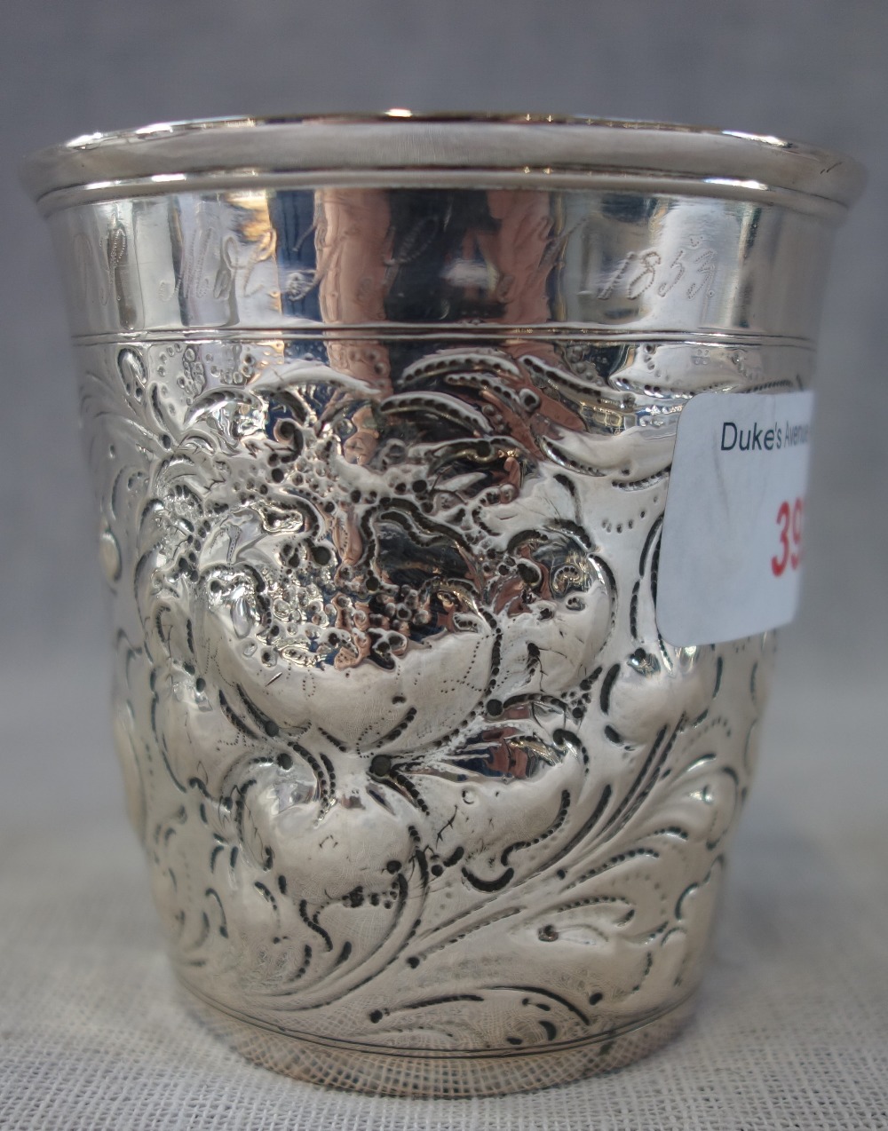 AN EMBOSSED SILVER BEAKER, 8.3cm high, approx 3.80oz