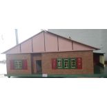 A VINTAGE 1950S DOLL'S HOUSE in the form of a bungalow, with metal framed windows, 36cm high x