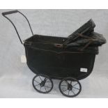 A VINTAGE 1920S DOLL'S PRAM with black coachwork and wire wheels and folding hood