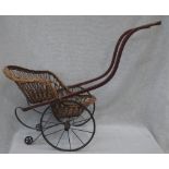 A VICTORIAN CHILD'S PERAMBULATOR with a wicker chair, red line-painted wooden frame and iron