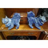 A PAIR OF CHINESE BLUE GLAZED CERAMIC LIONS/DOGS with bared teeth and bulging eyes