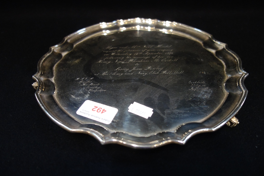 A SILVER SALVER with scalloped edge and shell feet, engraved inscription, 25cm diam