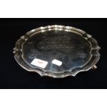 A SILVER SALVER with scalloped edge and shell feet, engraved inscription, 25cm diam