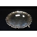 A SILVER SALVER with scalloped edge and hoof feet, 20cm diam