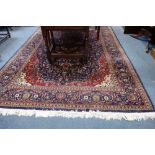 A RED GROUND PERSIAN DESIGN CARPET,with central blue medallion and all over floral decoration, 297cm